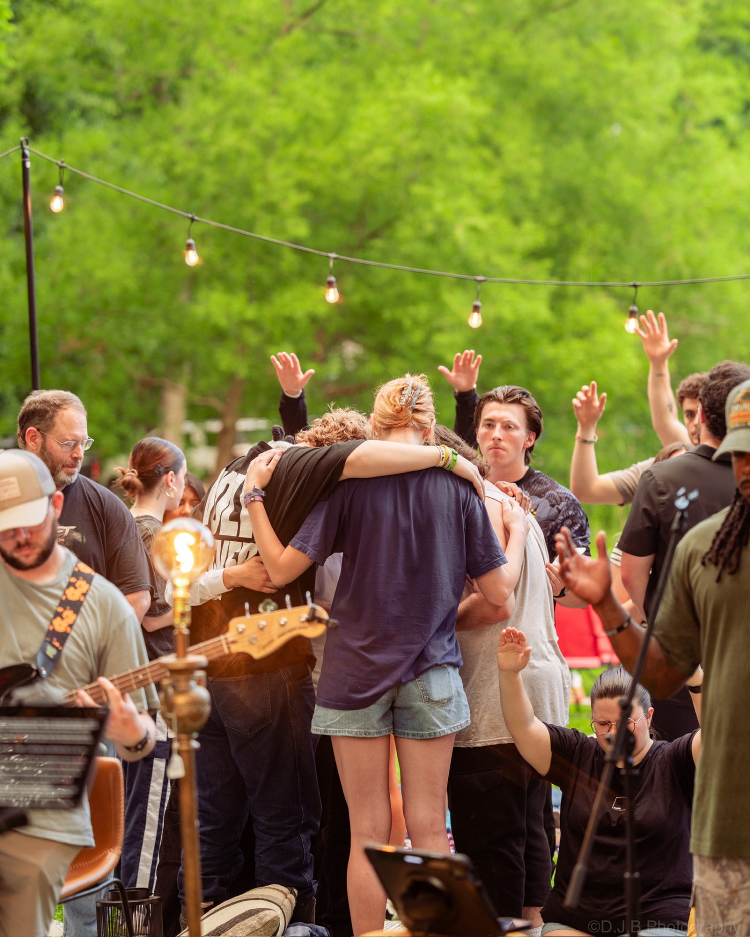 A circle of people praying together outdoors at a Sunday S'mores gathering
