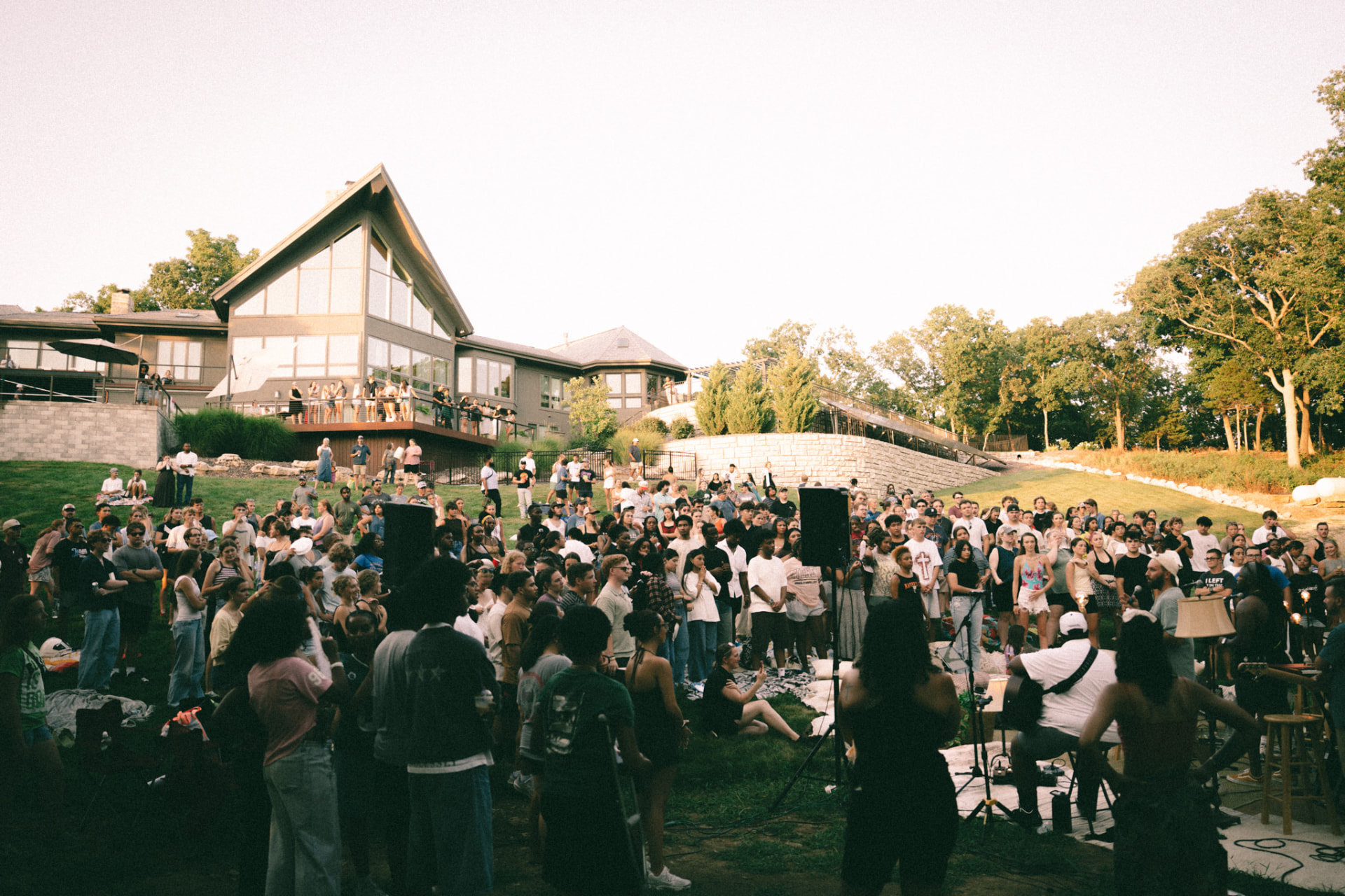 A crowd gathered on the lawn at golden hour outside a Sunday S'mores host home