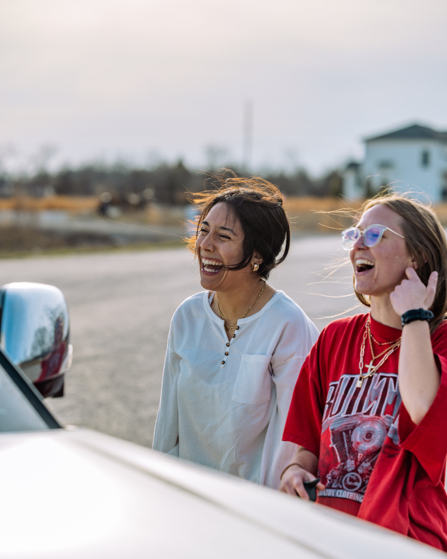Two friends laughing together by a truck on the way to a Sunday S'mores gathering